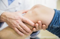 Huisarts onderzoekt patiënt met vocht in de knie / Bron: Denis Simonov/Shutterstock.com
